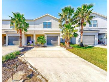 Inviting two-story townhome featuring a well-maintained lawn, driveway, garage, and lovely palm trees at 4781 Vignette Way, Sarasota, FL 34240