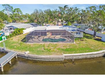 Aerial view of a single-story home with a pool and private dock on a canal at 4780 Butterfly Ne Pl, St Petersburg, FL 33703