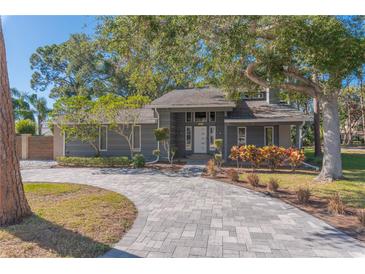 Gray house with a paved driveway, landscaping, and mature trees at 7850 134Th St, Seminole, FL 33776