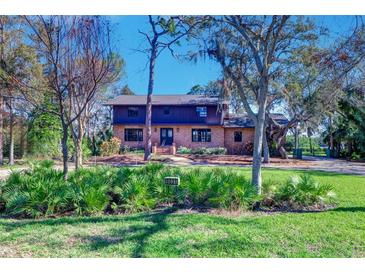 Brick house with dark trim, mature landscaping, and a spacious lawn at 9031 Baywood Park Dr, Seminole, FL 33777