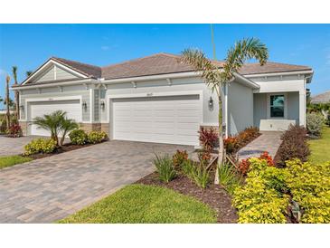 Charming home featuring a well-manicured lawn, a brick driveway, and a two-car garage at 18475 Green Garden Ct, Venice, FL 34293