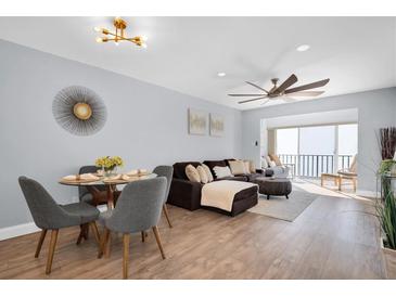 Bright living room featuring a modern ceiling fan, a dark brown couch and a sliding glass door at 2060 Marilyn St # 241, Clearwater, FL 33765