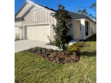 Two-car garage, landscaped yard, and neutral color palette at 3743 Nandina Cir, Sun City Center, FL 33573