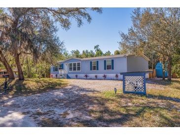 Single-wide manufactured home with light blue siding, situated on a spacious lot with mature trees at 9615 Xenia St, New Port Richey, FL 34654