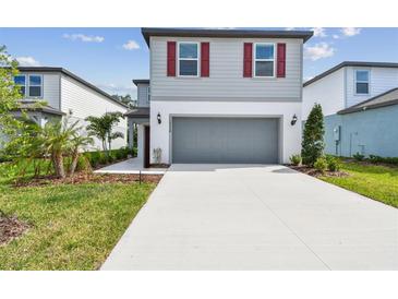 Charming two-story home with gray exterior, red shutters, a concrete driveway and attached two-car garage at 10524 Hidden Banks Gln, Parrish, FL 34219