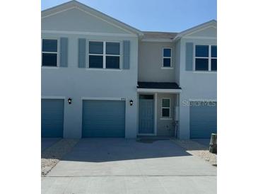 Charming townhome featuring a one-car garage and light blue accents at 4592 Pleasant Ave, Palm Harbor, FL 34683