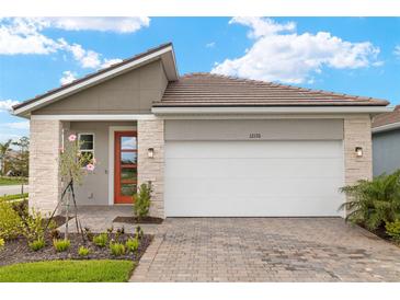 Charming single-story home featuring a brick driveway, stone accents, and a bright orange front door at 12170 Meditation Trl, Venice, FL 34293