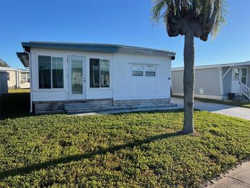 White single-wide manufactured home with a small lawn and palm tree at 13225 101St St # 451, Largo, FL 33773