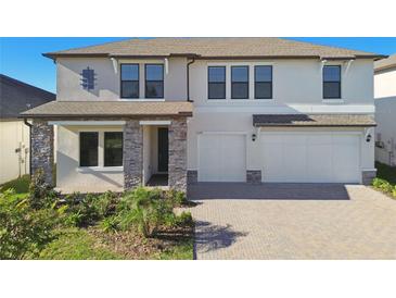 Charming home featuring stone accents, a paved driveway, and a three-car garage at 21291 Snowy Orchid Ter, Land O Lakes, FL 34637