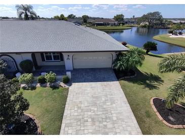 Inviting front of home with manicured lawn, stone paver driveway, and view of the adjacent pond at 1506 Bentwood Dr, Sun City Center, FL 33573