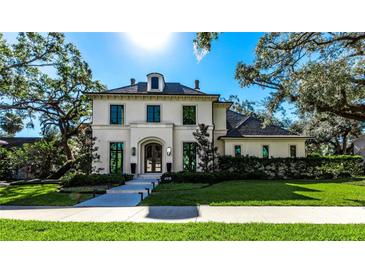 Elegant two-story home with manicured lawn and sophisticated architectural details under a sunny sky at 4518 W Rosemere Rd, Tampa, FL 33609