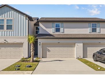 Two-story townhome featuring a neutral color palette, a two-car garage, and a manicured lawn at 7689 Imagination Pl, Wesley Chapel, FL 33545