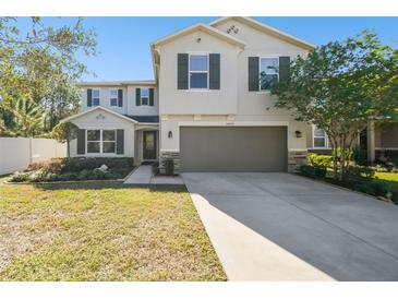 Two-story house with a neutral color scheme, two-car garage, and landscaped front yard at 10703 Aldo Moro Dr, Wimauma, FL 33598