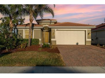 One-story home with a two-car garage, landscaped front yard, and brick paver driveway at 19308 Yellowtail Ct, Venice, FL 34292