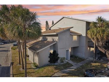 Two-story condo building with light-grey exterior, landscaping, and parking at 6336 Newtown Cir # 36A1, Tampa, FL 33615