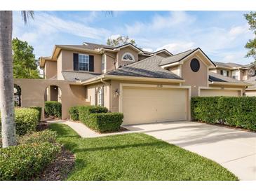 Tan two-story townhome with a two-car garage and manicured landscaping at 1339 Lahara Way, Trinity, FL 34655