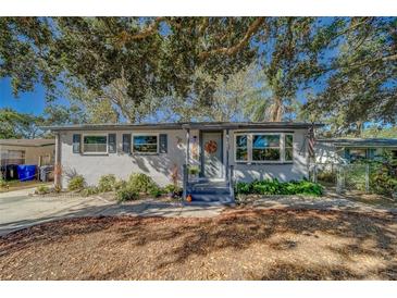 Charming single story home with gray exterior, landscaping, and large oak tree at 1638 St Catherine W Dr, Dunedin, FL 34698