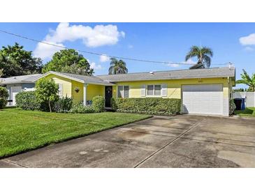 Cute yellow house with a green lawn and driveway at 8800 Sunlit Cove Ne Dr, St Petersburg, FL 33702