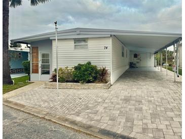 White single-wide mobile home with carport and landscaped walkway at 9790 66Th N St # 74, Pinellas Park, FL 33782