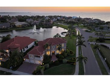 Stunning waterfront home with lush landscaping, fountain, and a beautiful tile roof at sunset at 1414 Alhambra Dr, Apollo Beach, FL 33572