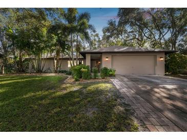 House exterior featuring a two-car garage and lush landscaping at 815 Village Way, Palm Harbor, FL 34683