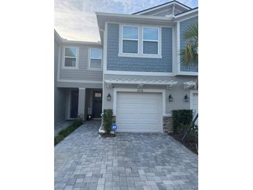 Two-story townhome with gray siding, white garage door, and paved driveway at 8518 Primrose Willow Pl, Odessa, FL 33556