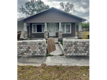 Gray house with stone pillars and a low stone wall in the front at 3505 E Mcberry St, Tampa, FL 33610