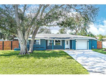 Charming blue home with large front yard, mature trees, and a modern wood fence at 1466 Laconia W Dr, Clearwater, FL 33764