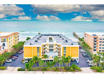 Aerial view of beachfront condo building with ocean and pier views, parking, and lush landscaping at 16308 Gulf Blvd # 303, Redington Beach, FL 33708
