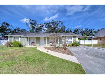 Charming single-story house with a green exterior, landscaped lawn, and covered parking at 6411 Crystal Brook Dr, Tampa, FL 33625