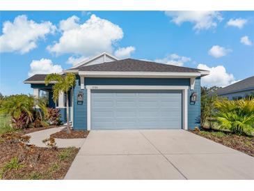 A charming one-story home with a blue exterior, two-car garage, and landscaped yard at 13584 Old Creek Ct, Parrish, FL 34219