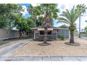 Cute bungalow with palm trees, a paved driveway and a well-maintained front yard at 4042 Boulder Dr, New Port Richey, FL 34653