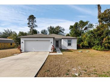 Newly constructed home with a white exterior, two-car garage, and landscaped yard at 5193 Deltona Blvd, Spring Hill, FL 34606