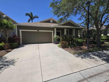 Charming single-story home featuring a two-car garage, well-manicured landscaping, and a covered front porch at 8451 Karpeal Dr, Sarasota, FL 34238
