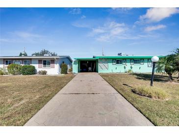 Mint green house with carport and landscaped yard at 1535 Council Dr, Sun City Center, FL 33573