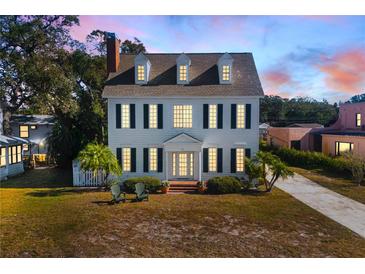 Two-story white house with black shutters, charming front porch, and manicured lawn at 55 Edgewater Dr, Dunedin, FL 34698