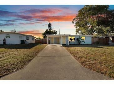 Cute light blue house with a yellow door, covered carport, and well-manicured lawn at 11950 105 N Ln, Largo, FL 33773