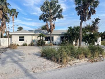 White single story home with palm trees and a large driveway at 909 Mandalay Ave, Clearwater Beach, FL 33767