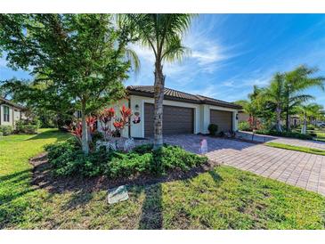 Two-car garage, landscaped yard, and paver driveway of this beautiful home at 12115 Amica Loop, Venice, FL 34293