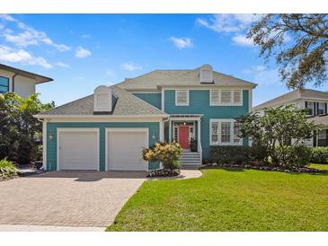 Charming two-story home with a well-manicured lawn, brick driveway and vibrant red door at 5004 W Leona St, Tampa, FL 33629