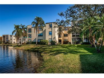 Condo building with water view, lush landscaping, and palm trees at 14130 Rosemary Ln # 4311, Largo, FL 33774