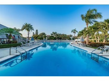 Inviting community pool with palm trees and lounge chairs at 14130 Rosemary Ln # 4311, Largo, FL 33774