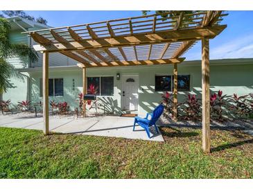 Inviting home exterior featuring a pergola, landscaping, and a blue chair at 8390 64Th N St, Pinellas Park, FL 33781