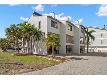 Charming condo with white stucco exterior, balconies, palm trees, and paved driveway at 9901 1St E St # F, Treasure Island, FL 33706