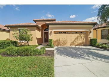Single-story house with tan walls, a two-car garage, and lush landscaping at 127 Silver Falls Dr, Apollo Beach, FL 33572