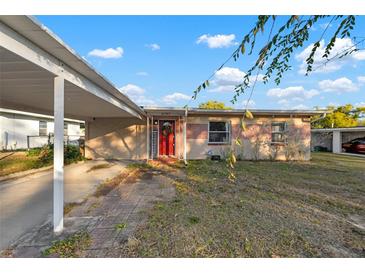 Charming single-story home with a covered carport and a bright red front door at 8707 Beverly Dr, Temple Terrace, FL 33617