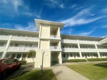 Condo building exterior, featuring a light-colored facade and lush landscaping at 1235 S Highland Ave # 2-206, Clearwater, FL 33756