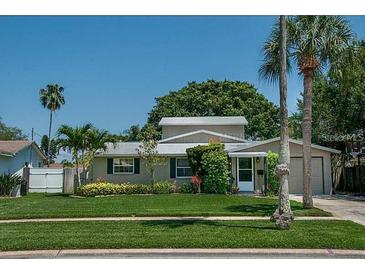 Tan house with well-manicured lawn, two palm trees, and attached garage at 5731 Venetian Ne Blvd, St Petersburg, FL 33703