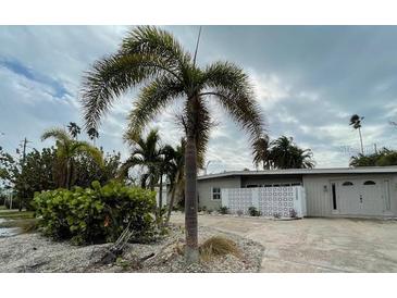 Light gray single story home with attached garage, palm trees, and landscaped yard at 16304 3Rd St, Redington Beach, FL 33708