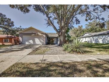 House exterior, featuring a light gray color, attached garage, and landscaping at 2042 Ridgelane Rd, Clearwater, FL 33755